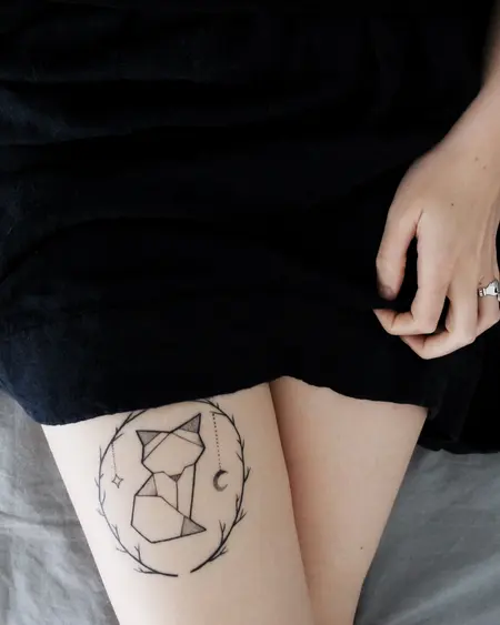 A fine-line geometric fox in a ring of leaves, on a thigh.